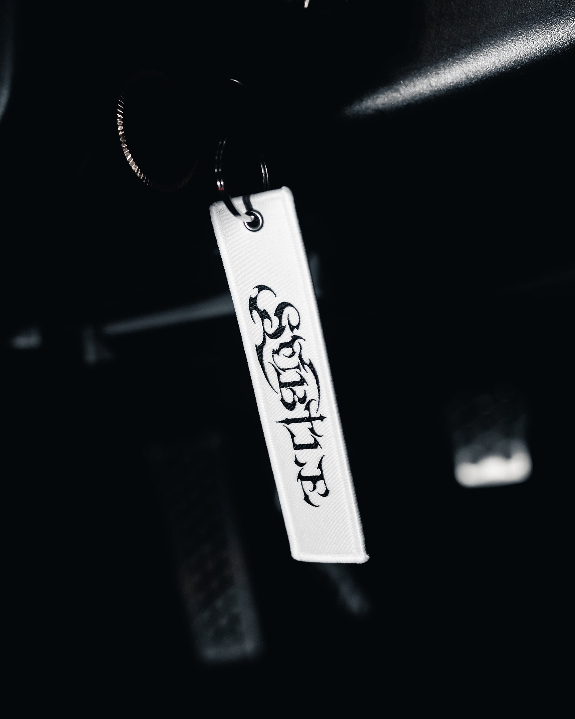 Metal keychain with 'SUBLIME' engraving on a dark background