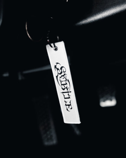 Metal keychain with 'SUBLIME' engraving on a dark background