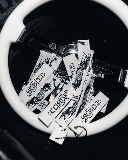 Collection of tattoo-style keychains on a white surface